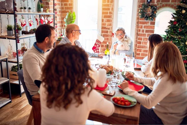 Family and friends dining at home celebrating christmas eve with traditional food and decoration, celebration of festive winter time