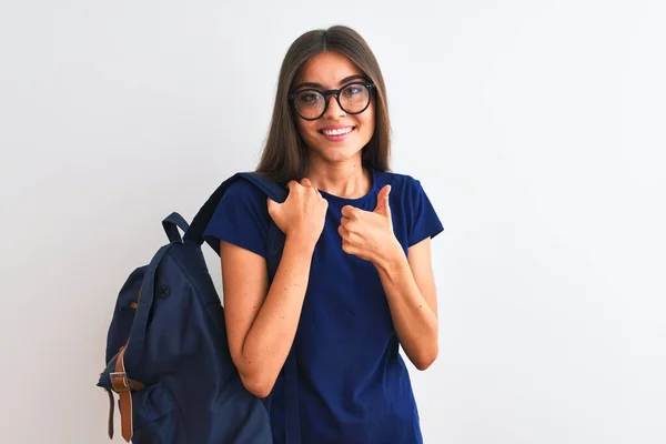 Young beautiful student woman wearing backpack and glasses over isolated white background happy with big smile doing ok sign, thumb up with fingers, excellent sign