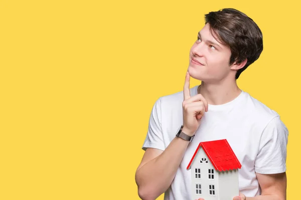 Joven Sosteniendo Casa Sobre Fondo Aislado Cara Seria Pensando Pregunta —  Fotos de Stock