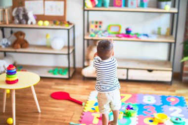 Anaokulunda bir sürü oyuncakla bekleyen güzel bir çocuk.