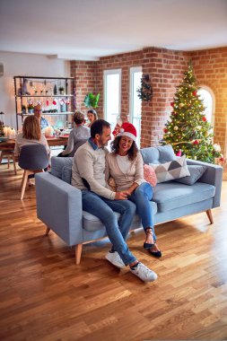 Noel arifesini evde geleneksel yemek ve dekorasyonla kutlayan aile ve arkadaşlar kanepede oturup romantik yaşlı çiftler gibi sohbet ediyorlar.