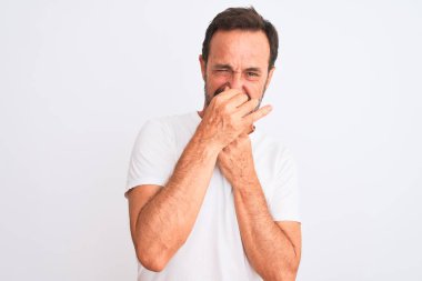 İzole edilmiş beyaz arka plan üzerinde sıradan bir tişört giyen orta yaşlı yakışıklı bir adam pis ve iğrenç bir koku alıyor. Nefesini burnunda tutuyor. Kötü koku konsepti.