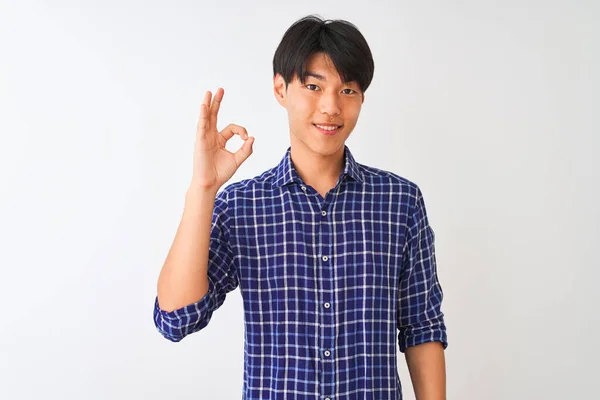 孤立した白い背景の上に立つカジュアルな青いシャツを着て若い中国人男性は 手と指でOkの署名を行う積極的な笑顔 成功した表現 — ストック写真