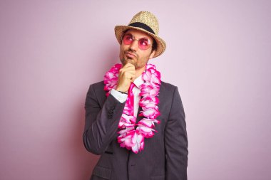 Takım elbiseli genç işadamı gözlüklü Hawai leyleği izole edilmiş pembe arka planda soru soran ciddi bir yüz, çok karışık bir fikir.