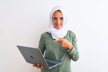 Genç Arap iş kadını tesettüre girip dizüstü bilgisayar kullanıyor. El ve parmağıyla işaret ederek çok mutlu.