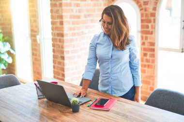 Genç iş kadını bilgisayar dizüstü bilgisayar kullanarak çalışan masanın yanında duran, ofiste modern yönetici kız