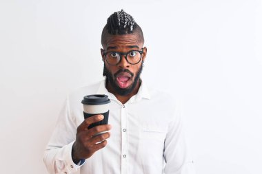 Örgü örgülü Afrikalı Amerikalı iş adamı beyaz arka planda kahve içiyor. Şaşırmış bir yüz ifadesinden korkuyor ve heyecanlanıyor.