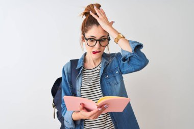 Sırt çantası takan kızıl saçlı kız izole edilmiş beyaz arkaplan üzerine kitap okuyor. Elleri başının üstünde, utanç ve şaşkınlık dolu, sinirli ve hayal kırıklığına uğramış bir halde. Hata için korku ve üzüntü.