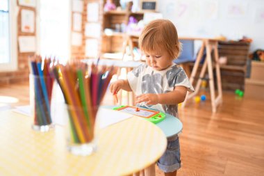 Anaokulundaki oyuncakların etrafında dijital tahta kullanarak sevimli bebek çizimi