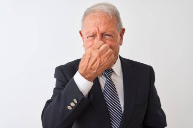 İzole edilmiş beyaz arka planda takım elbise giyen kıdemli gri saçlı işadamı pis ve iğrenç bir koku alıyor, nefes nefese kalmış, parmakları burnunda. Kötü koku konsepti.