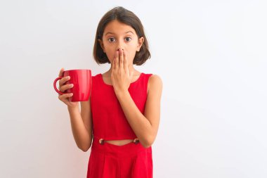 Güzel bir kız çocuğu elinde kırmızı çay fincanıyla izole edilmiş beyaz arka planda duruyor. Ağzı kapalı, utancından ağzı açık, korkusunun dışa vurumu, sessizlikten korkması, gizli bir konsept.