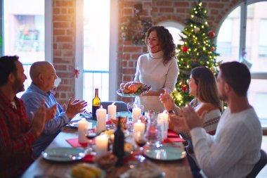Mutlu ve kendinden emin gülümseyen güzel bir aile. Kavrulmuş hindiyi göstermek ve evde Noel 'i kutlamak.