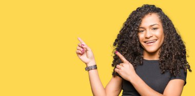 Gülümseyen ve iki ile işaret kamera bakarak kıvırcık saçlı Genç güzel kadın eller ve yan parmak.