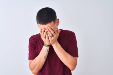 Genç yakışıklı adam izole edilmiş arka planda duruyor. Ağlarken yüzünü ellerle kapatan üzgün bir yüz ifadesi var. Depresyon kavramı.