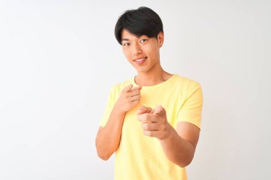 Sarı günlük tişört giyen Çinli bir adam izole edilmiş beyaz arka planda durup mutlu ve komik yüzlü parmakları kameraya doğrultuyor. İyi enerji ve titreşimler.