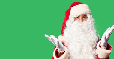 Orta yaşlı yakışıklı, Noel Baba kostümü ve sakal takmış neşeli gülümseyerek el ele tutuşan ve kabul gören bir adam..