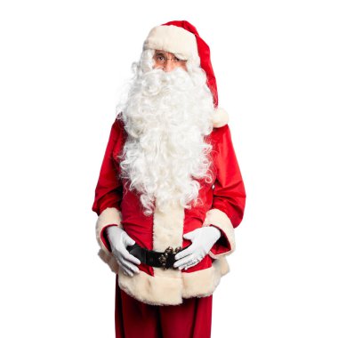 Orta yaşlı yakışıklı adam Noel Baba kostümü ve sakal takmış yüzünde ciddi bir ifadeyle rahatlamış duruyor. Basit ve doğal bir şekilde kameraya bakıyorsun..