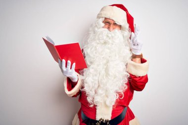 Orta yaşlı bir adam, Noel Baba kostümü giyip izole edilmiş beyaz arka plan üzerinde kitap okuyor. Umut ve gözler kapalı bir şekilde gülümsüyor. Şans ve batıl inanç..