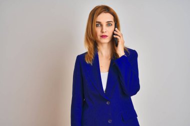 Kafkasyalı zarif bir iş kadını izole bir arka planda telefonla konuşuyor. Zeki bir yüz ifadesiyle ciddi ciddi düşünüyor.
