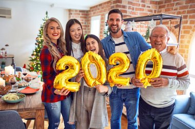 Mutlu ve kendinden emin gülümseyen güzel bir aile. Noel 'i kutlamak için elinde balonlarla dikiliyorum.