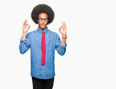 Gözlük ve kırmızı kravat giyen afro saçlı genç Afro-Amerikalı iş adamı rahatla ve gülümseyen gözlerle kapalı parmak jestle meditasyon yapıyor. Yoga kavramı.