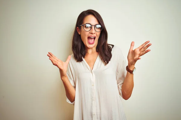 Young beautiful woman wearing shirt and glasses standing over white isolated background smiling and looking at the camera pointing with two hands and fingers to the side.