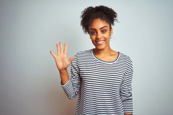 African american woman wearing navy striped t-shirt standing over isolated white background showing and pointing up with fingers number five while smiling confident and happy.
