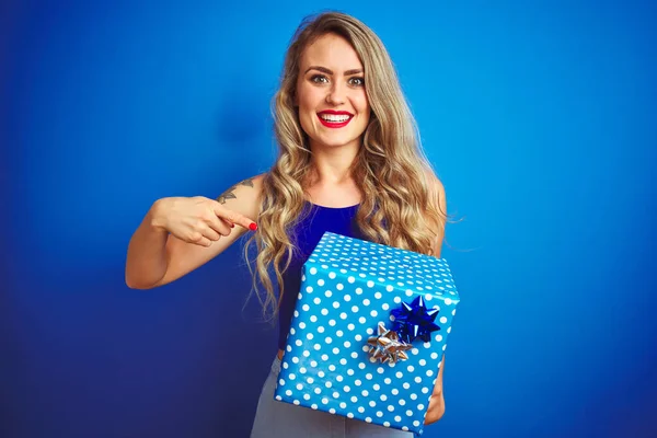 Νεαρή Όμορφη Γυναίκα Κρατώντας Δώρο Γενεθλίων Πάνω Από Μπλε Απομονωμένο — Φωτογραφία Αρχείου