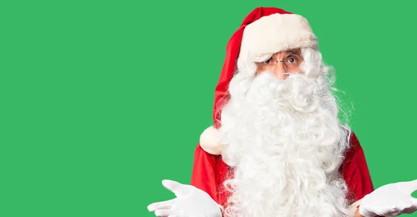 中年英俊男子 身穿圣诞老人服装 留着胡子 毫无头绪地站在那里 与张开的双臂混淆不清 一点概念都没有 — 图库照片