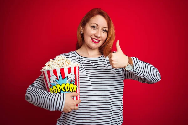 Joven Hermosa Pelirroja Comiendo Palomitas Maíz Sobre Fondo Rojo Aislado —  Fotos de Stock