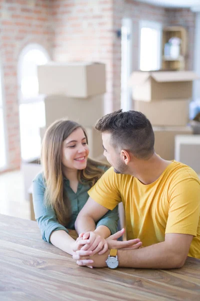 Junges schönes Paar sitzt zu Hause auf dem Tisch und umarmt sich — Stockfoto