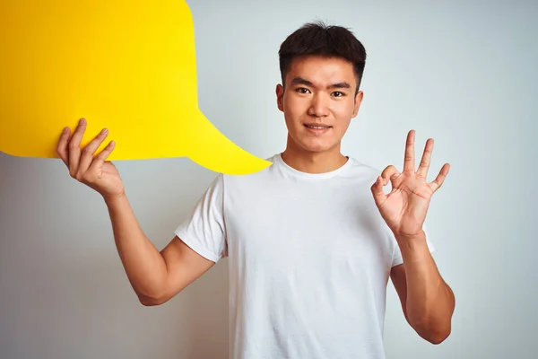 亚裔男子手持话筒站在孤零零的白色背景上 手握手签 很好的符号 — 图库照片