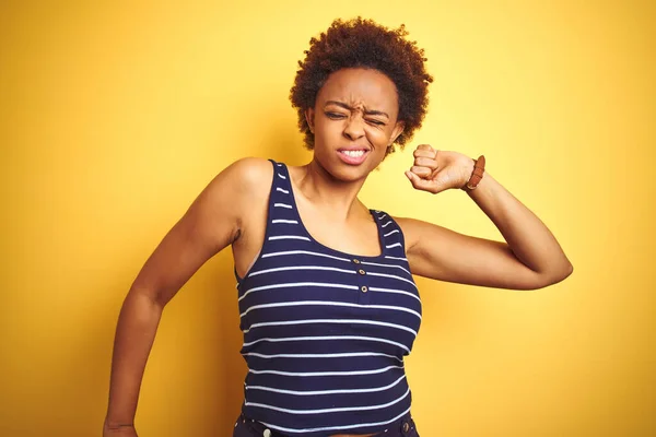 Beauitul african american woman wearing summer t-shirt over isolated yellow background stretching back, tired and relaxed, sleepy and yawning for early morning