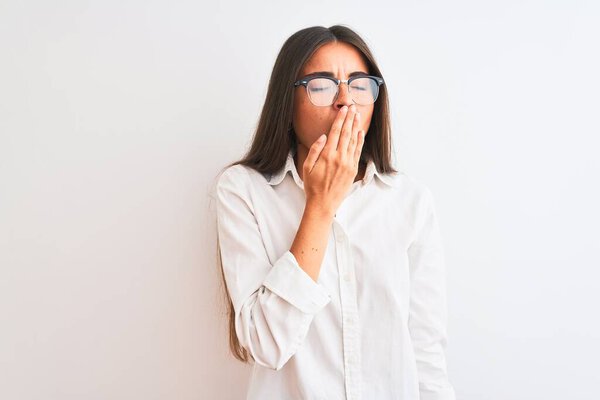 Young beautiful businesswoman wearing glasses standing over isolated white background bored yawning tired covering mouth with hand. Restless and sleepiness.