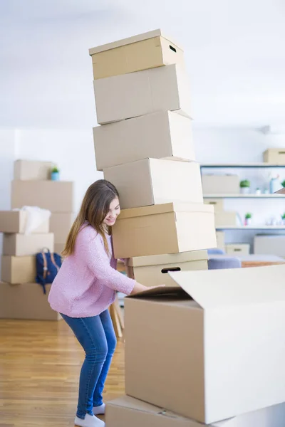 Young woman moving to a new apartment, holding a pile of cardboa
