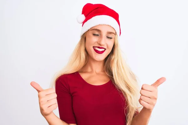 孤立した白い背景の成功の印の上にクリスマスのサンタの帽子を身に着けている若い美しい女性は手で肯定的なジェスチャーをする 親指を笑顔と幸せ 陽気な表情と勝者のジェスチャー — ストック写真