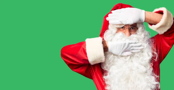 中年英俊男子 身穿圣诞老人服装 蓄着胡子 站在那里欢快地嬉笑着 用手摸着脸看了一眼 很惊讶也很兴奋 — 图库照片