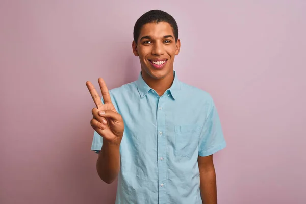 年轻英俊的阿拉伯男子 身穿蓝色衬衫 站在孤立的粉色背景上 带着自信和快乐的笑容 用手指指了指二号 — 图库照片