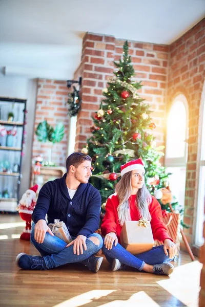 Casal Jovem Vestindo Chapéu Papai Noel Sentado Chão Torno Árvore — Fotografia de Stock