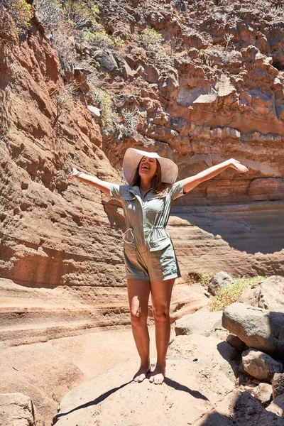 Young beauitufl hiker woman trekking natural orange mountain with arms raised celebrating summer holidays