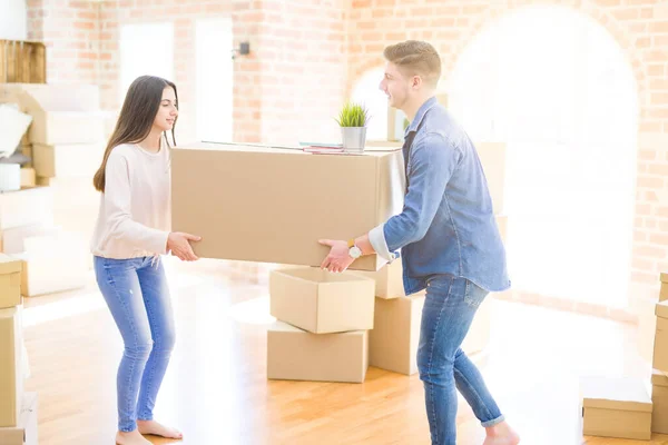 Schönes junges Paar, das verliebt lächelt und einen großen Karton in der Hand hält — Stockfoto