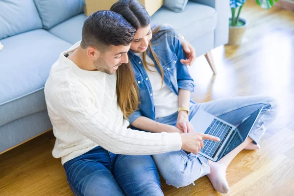 Jong stel zittend op de verdieping van nieuw huis met behulp van computer lap — Stockfoto