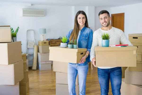 Junges Paar zieht in ein neues Zuhause und lächelt glücklich mit Karton — Stockfoto