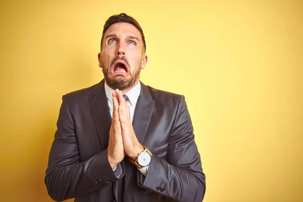 Joven Hombre Negocios Guapo Sobre Fondo Aislado Amarillo Mendigando Orando —  Fotos de Stock