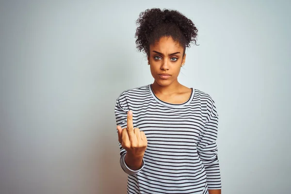 African american woman wearing navy striped t-shirt standing over isolated white background Showing middle finger, impolite and rude fuck off expression