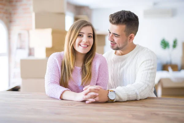 Young beautiful couple sitting on the table at home, hugging in