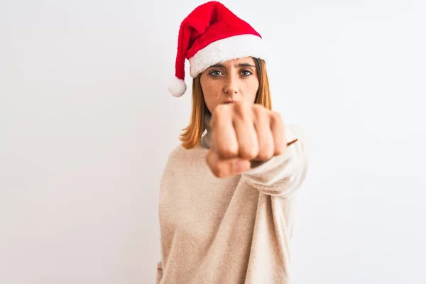 美しい赤毛の女性は孤立した背景の上にクリスマスの帽子をかぶって戦うために拳をパンチ 積極的かつ怒っている攻撃 脅威と暴力 — ストック写真