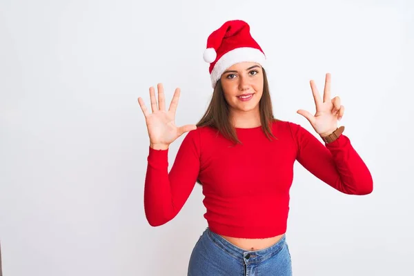年轻美丽的女孩戴着圣诞圣诞圣诞礼帽 站在孤独的白色背景上 用手指指着八号 面带微笑 自信而快乐 — 图库照片