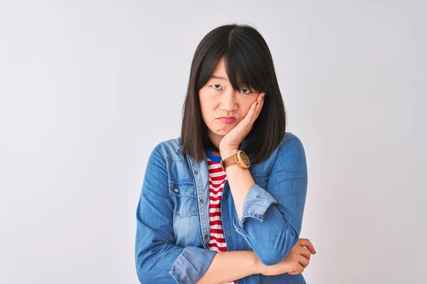 Chinese woman wearing denim shirt and red striped t-shirt over isolated white background thinking looking tired and bored with depression problems with crossed arms.