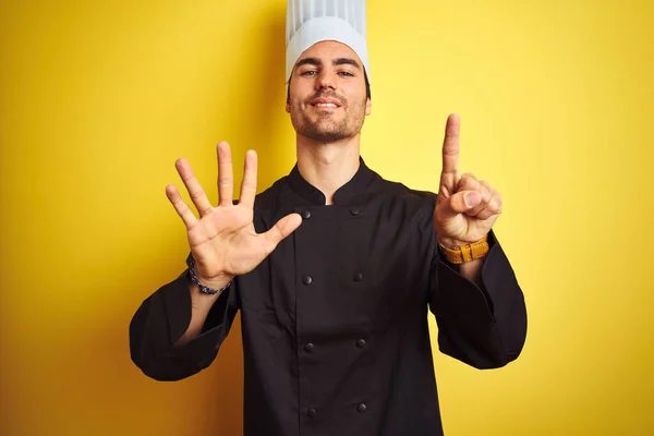 身穿制服 头戴帽子的年轻厨师站在孤立的黄色背景上 带着自信和快乐的笑容 用手指指了指六号 — 图库照片